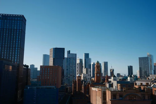 Skyline of Manchester city featuring the iconic Beetham Tower under a bright blue sky