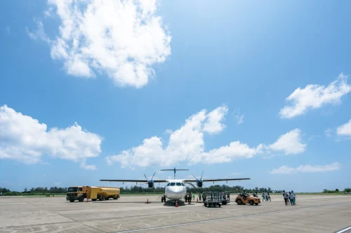 A Druk Air ATR 72 is parked on the apron with ground crew preparing for departure.