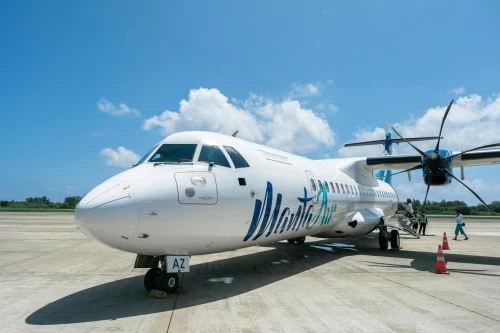 A Samoa Airlines ATR 72 is parked on the apron with ground crew attending to it.