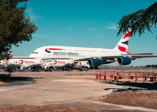 A British Airways Airbus A380 is parked at the apron alongside Total Airlines fuel trucks.