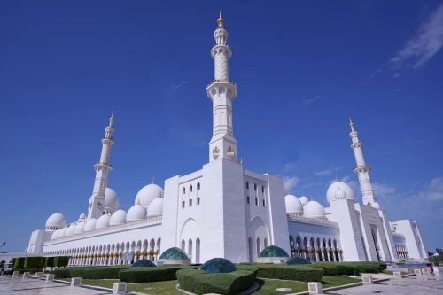 Stunning view of the Sheikh Zayed Grand Mosque showcasing its iconic white domes and minarets against a clear blue sky