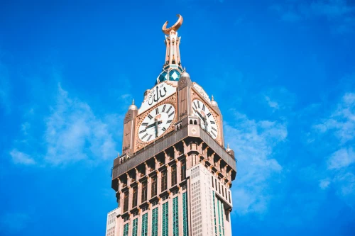 Stunning view of the iconic Abraj Al Bait Clock Tower against a vibrant blue sky in Mecca, Saudi Arabia