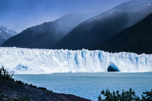 Stunning view of the Perito Moreno Glacier with mountains and blue sky in the background, perfect for travel inspiration