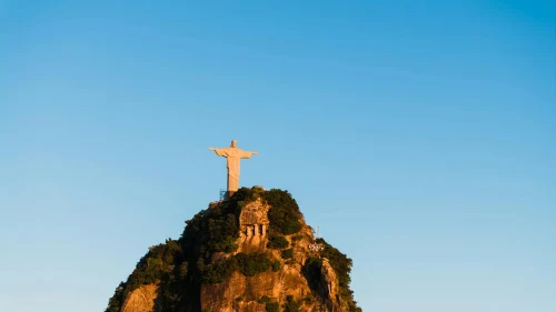 view of Christ the Redeemer statue atop Corcovado Mountain in Rio de Janeiro under a bright blue sky