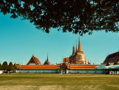 Wide-angle view of the Grand Palace in Bangkok with blue sky and lush trees