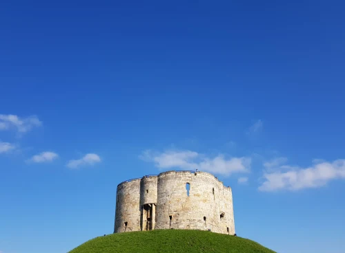Clifford's Tower in York, England, against a vivid blue sky on a sunny day