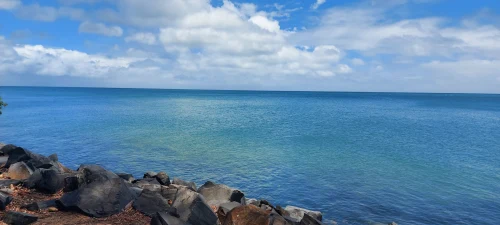 Scenic view of Hervey Bay, QLD, showing calm ocean and rocky shoreline under a blue sky