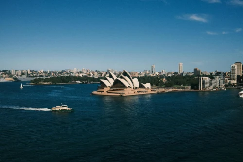 Panoramic view of Sydney Opera House with boat in the harbor under a clear blue sky