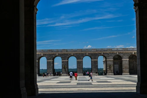 View of the Royal Palace courtyard in Madrid with people walking under a clear blue sky