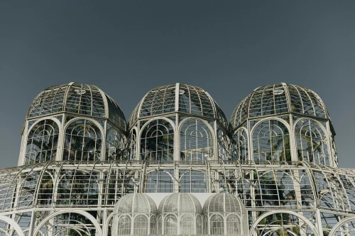 Modern greenhouse with steel and glass structure against a clear sky. Iconic architectural design