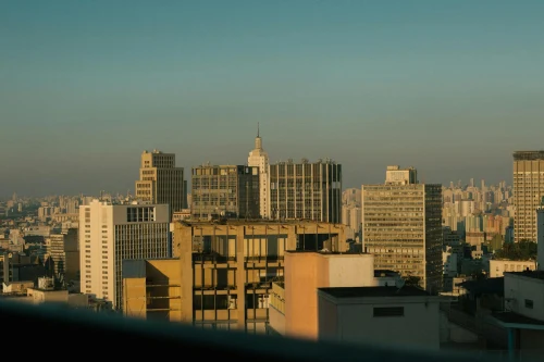 High skyscrapers of modern district located in middle near residential buildings of famous city against cloudless sky in sunny weather in daylight
