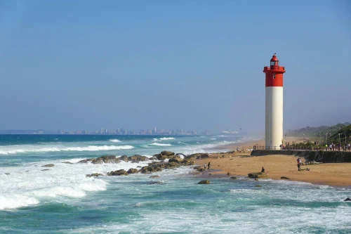 Explore the iconic Umhlanga Lighthouse against the backdrop of a vibrant blue sky and crashing waves in South Africa