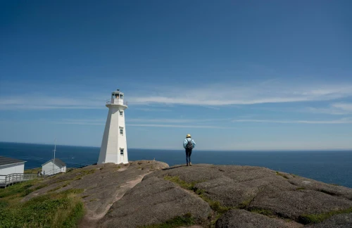 Woman hiking near Cape Spear Lighthouse with clear sky and sea view