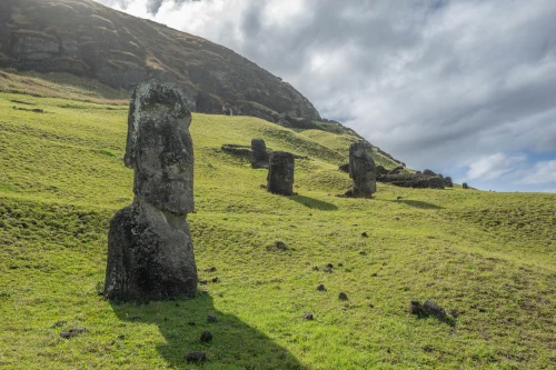 Iconic Moai statues set against lush green hills on Easter Island, Chile under a dramatic sky