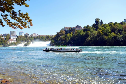 Tourists enjoying a boat tour on the Rhine River with Rhine Falls in the background, Switzerland