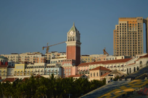 A clock tower surrounded by colorful coastal buildings under a clear blue sky