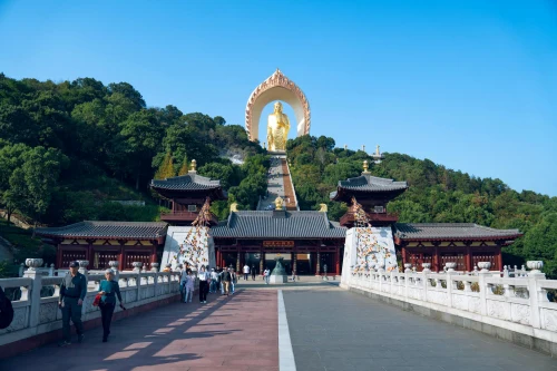 The majestic golden Buddha statue at Donglin Temple in Jiangxi, surrounded by lush greenery under a clear sky