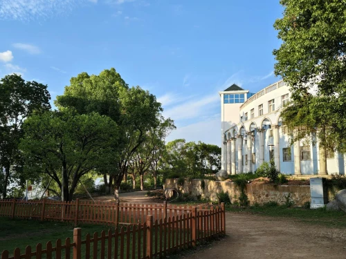 A white building surrounded by lush green trees and clear blue sky, creating a serene outdoor scene