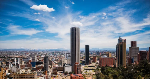 cityscape of Bogotá with the iconic Colpatria Tower under a vibrant blue sky