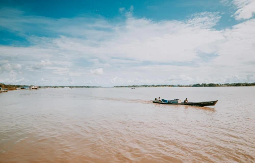 Iconic view of Leticia (LET), colombia — A motorboat glides through the Amazon River in Leticia, Colombia under a bright summer sky..