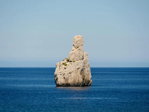 Stunning rock formation known as Finger of God in Ibiza against a serene blue sea and clear sky