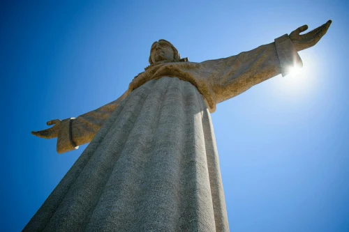 View of the iconic Cristo Rei statue in Almada, Portugal against a clear blue sky