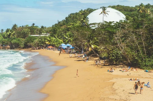 A vibrant beach scene in Rincón, Puerto Rico with people enjoying a sunny day by the sea