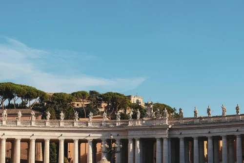 Explore the iconic colonnades and statues in the heart of Vatican City under a clear blue sky