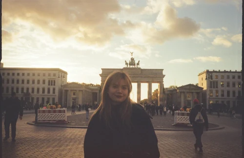 Portrait of a woman at Berlin's iconic Brandenburg Gate at sunset with vibrant skies