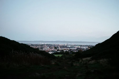 Distant view of Edinburgh cityscape framed by hills under a clear sky