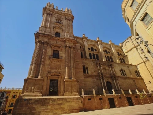 A detailed view of a historic cathedral tower in Málaga, showcasing its intricate architecture on a sunny day