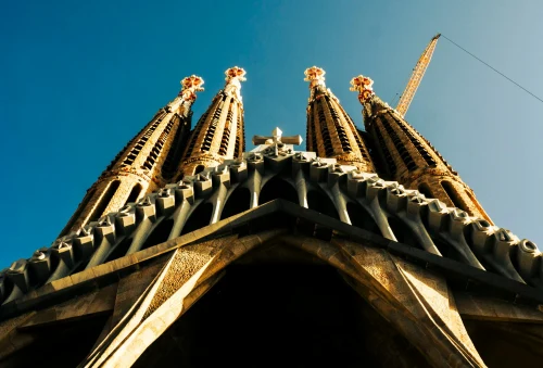 Low-angle view of the iconic Sagrada Familia spires in Barcelona, showcasing Gaudí's architectural marvel against a clear blue sky