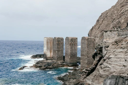 Rugged stone pillars at Santa Catalina's wild coastline in Spain, showcasing historic ruins against the Atlantic Ocean
