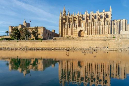 Beautiful view of Palma Cathedral, Mallorca, reflecting in calm water on a sunny day