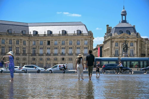 People enjoying a sunny day at Place de la Bourse in Bordeaux, France, with the iconic water mirror