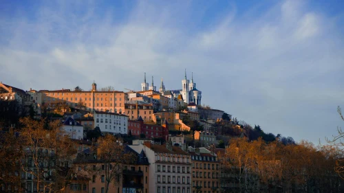A scenic view of Lyon's historic old town and Basilica of Notre-Dame de Fourvière basking in the warm evening light