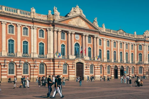 The iconic Capitole de Toulouse with people enjoying the sunny plaza in France