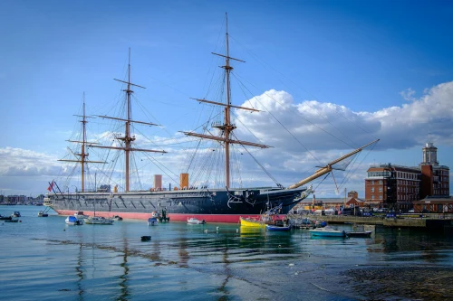 The iconic HMS Warrior, a 19th-century warship, docked in Portsmouth under a clear blue sky