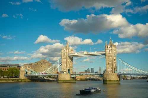 view of Tower Bridge, London, under a sunny blue sky with clouds