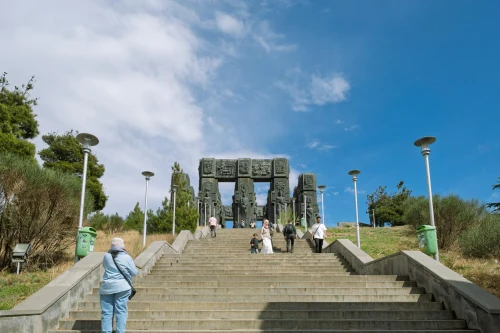 People visit the Chronicle of Georgia monument on a sunny day in Tbilisi