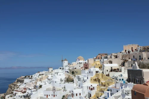 Explore the iconic whitewashed architecture of Oia, Santorini under a clear blue sky