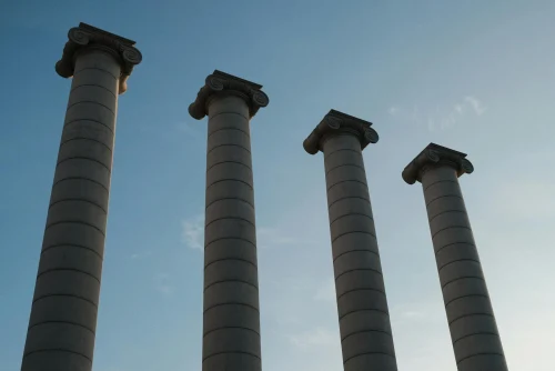 A low angle shot of Barcelona's iconic four columns under a clear blue sky, symbolizing Catalonian heritage