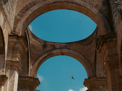 Elegant ancient brick arches of a historic ruin in Antígua, Guatemala, under a clear blue sky