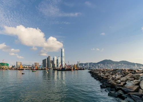 A stunning view of the Hong Kong skyline featuring the ICC and Victoria Harbour under a clear blue sky