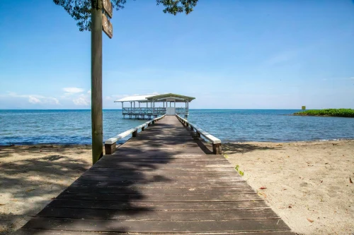 Wooden pier leading to a serene ocean view under a clear sky, ideal summer day