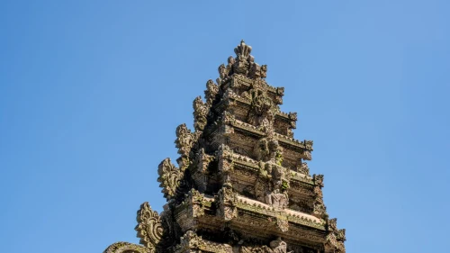 Detailed view of a traditional Balinese temple tower against a clear blue sky in Bali, Indonesia