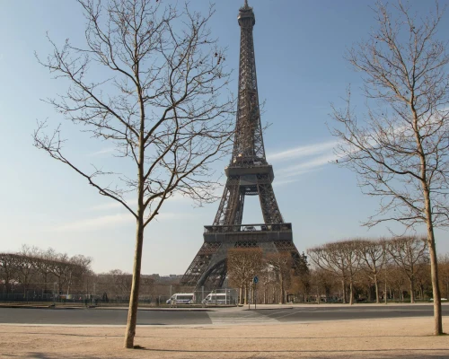 View of the Eiffel Tower in Paris, France, with bare winter trees and a blue sky