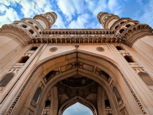 Low angle view of the iconic Charminar monument under a blue sky in Hyderabad, India