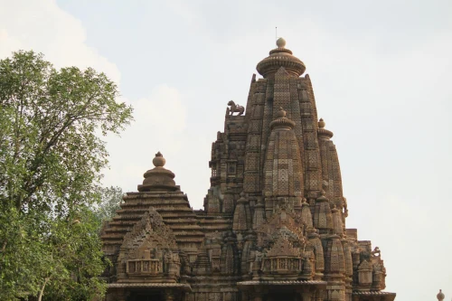 View of intricate stone carvings on a historic Khajuraho temple under a clear sky