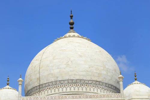 Close-up of the iconic marble dome of the Taj Mahal against a bright blue sky